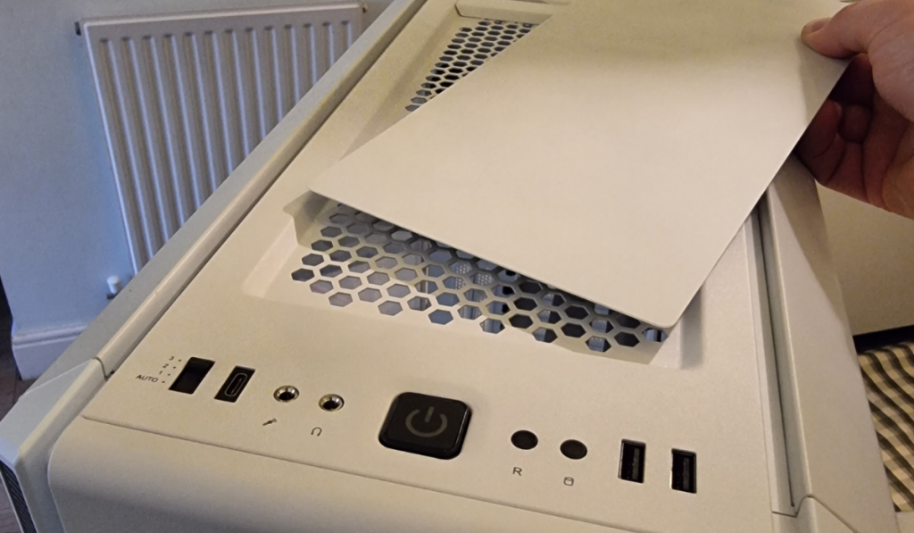 A photo of the lid being removed from the top of the PC case allowing the user to customise the case depending on the number of fans or size of the radiator that they have going into the roof of it.