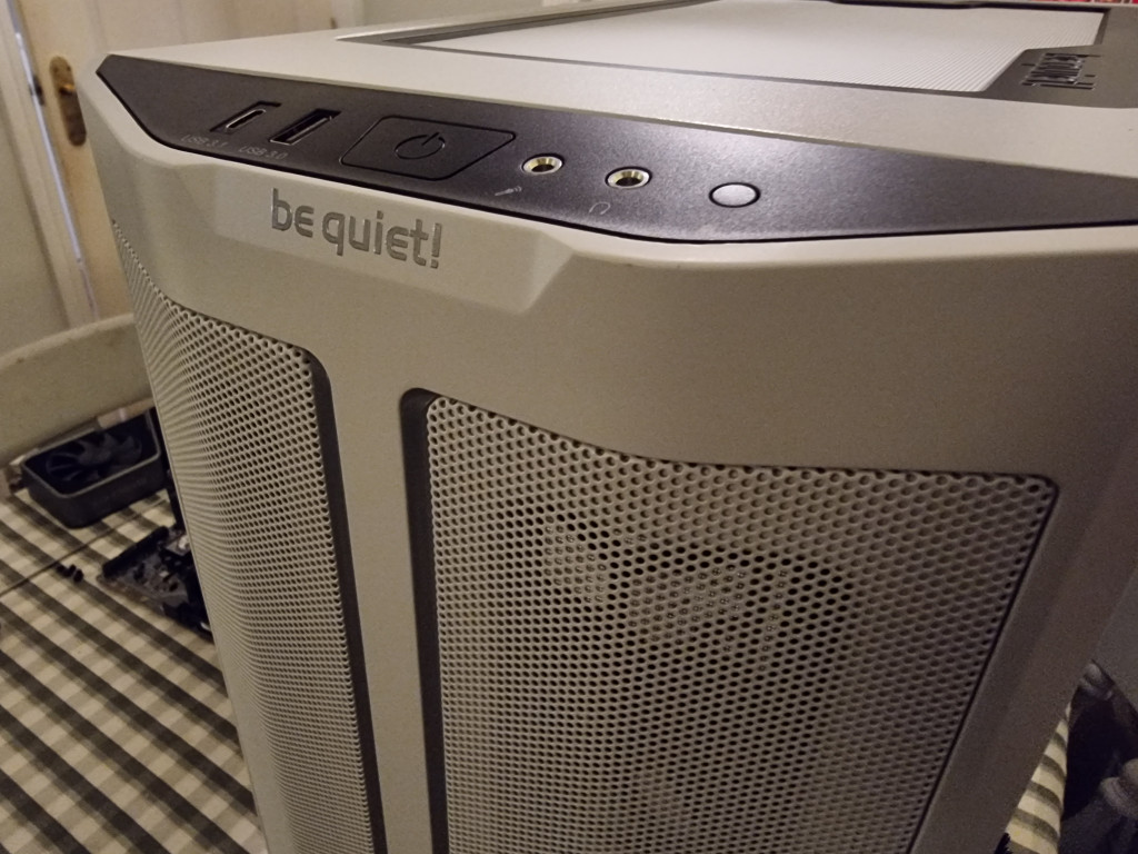 screenshot showing the front of a white bequiet pure base 500dx pc case. a White mesh front is visible with a black strip at the top front with the power buttons and input output functions.