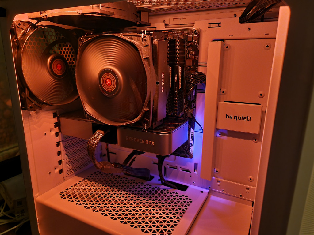screenshot showing the inside of the pc illuminated in orange. the mobo gives off an eerie blue glow at the bottom right-hand side. The extract and cpu fans are spinning as power floods through the system.