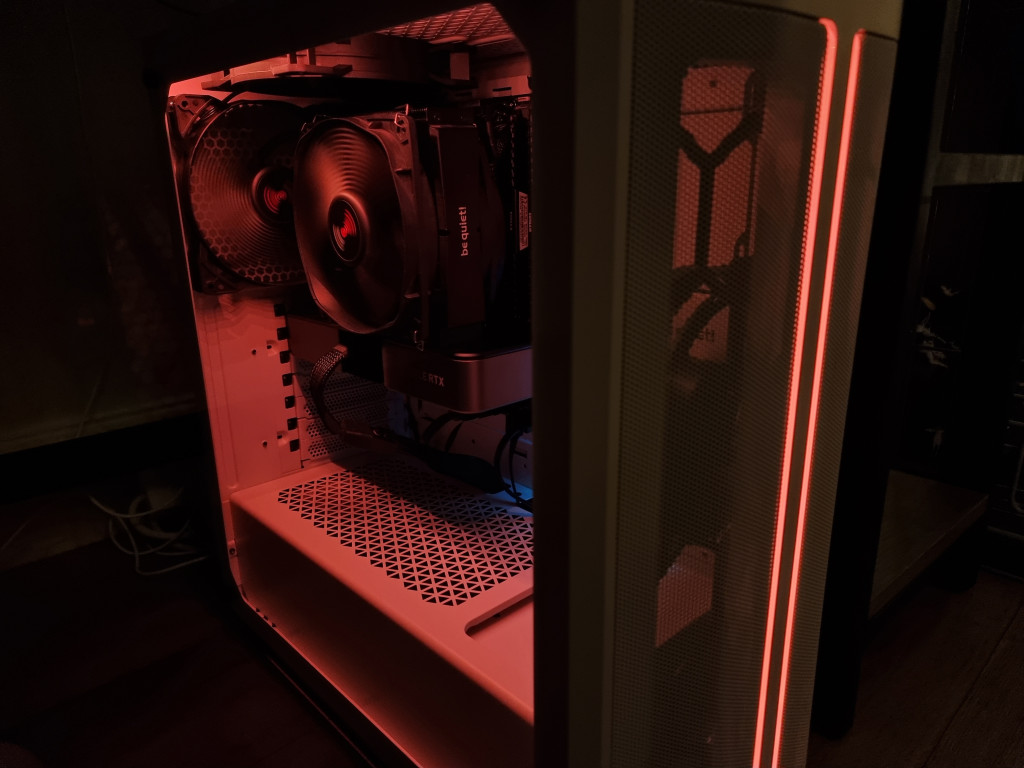 screenshot showing the bequiet pure base 500 dx illuminated. A twin strip of orange runs vertically down the front centrally while the inside of the pc is visible thanks to the glass door on the left of the case.