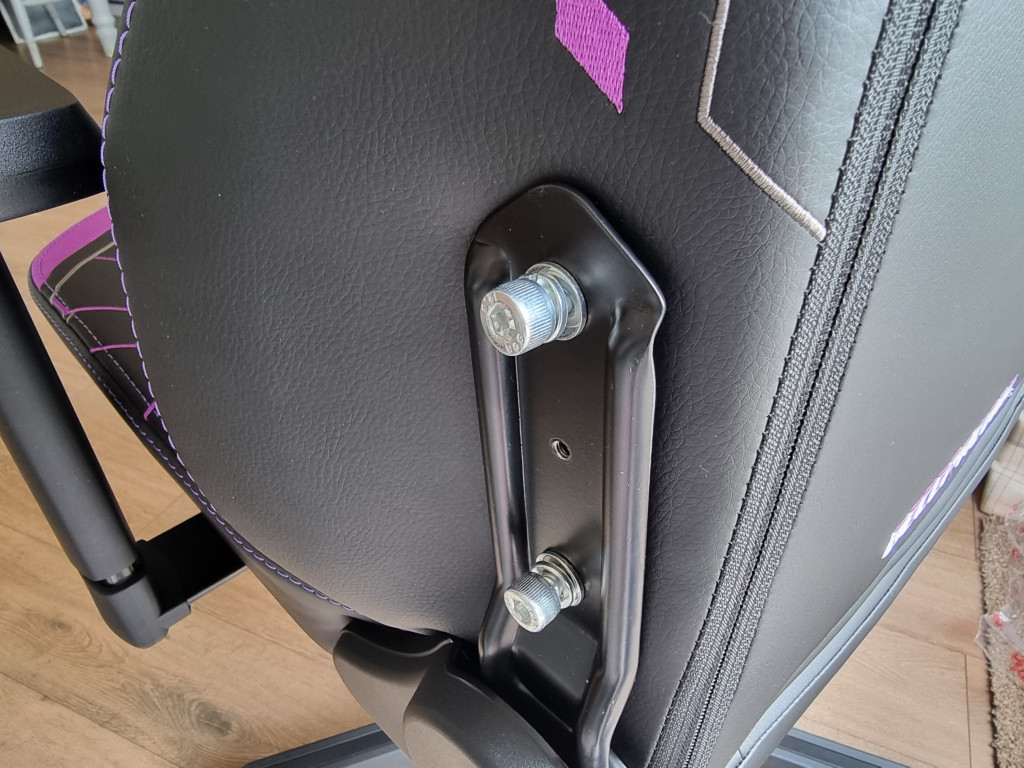 picture showing the side of the chair focussing on the black metal bracket that holds the seat back to the base. 2 silver bolts are in situ.
