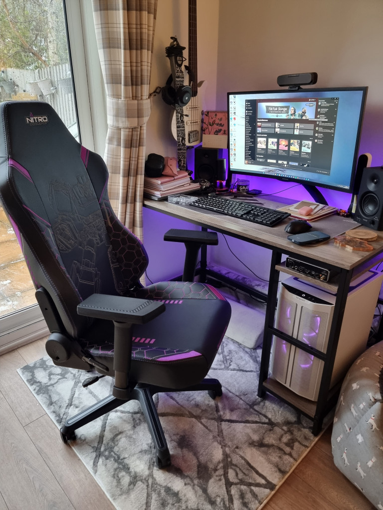 picture showing the constructed gaming chair beside a gaming desk. A purple glow is coming from the pc and desk.
