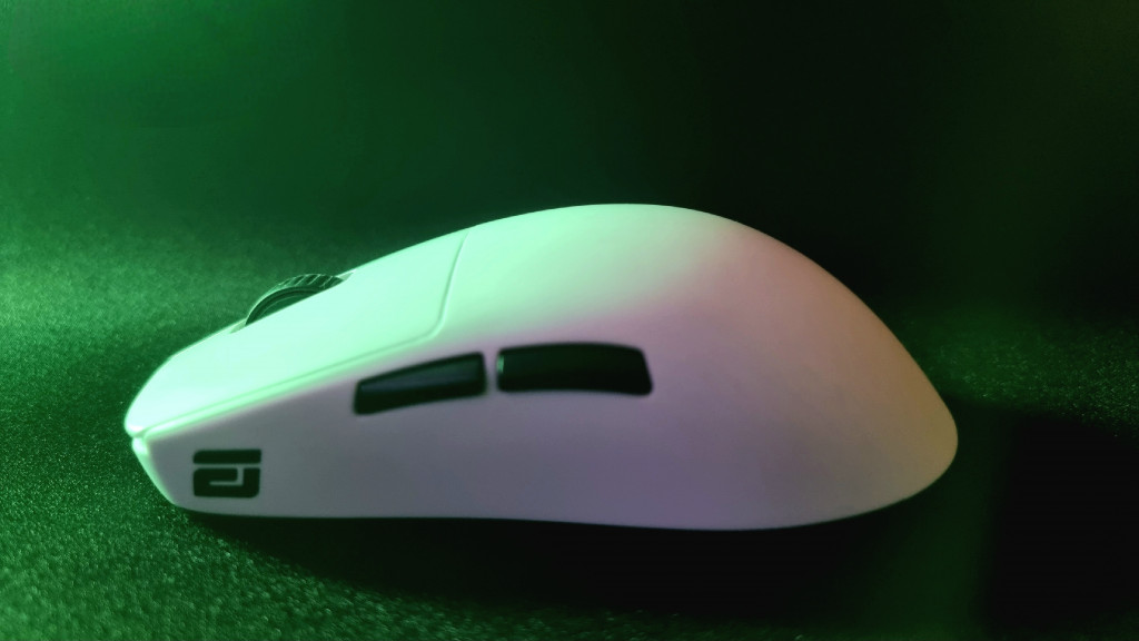 photo of the white endgame gear gaming mouse with the camera looking side on to it. The white of the mouse is contrasted by the black middle wheel on top and 2 side buttons. The endgame gear logo can be seen on the side as well. The mouse is bathed in an eerie green light.