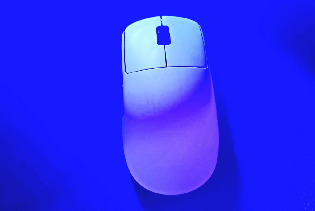 photo of the white endgame gear gaming mouse with the camera looking from above down onto the top of it. A blue light swamps and shows off its smooth contours.