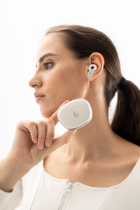 A side-profile of a person wearing the white NeoBuds Pro 2 earbuds, while holding up the matching white case close to the camera.