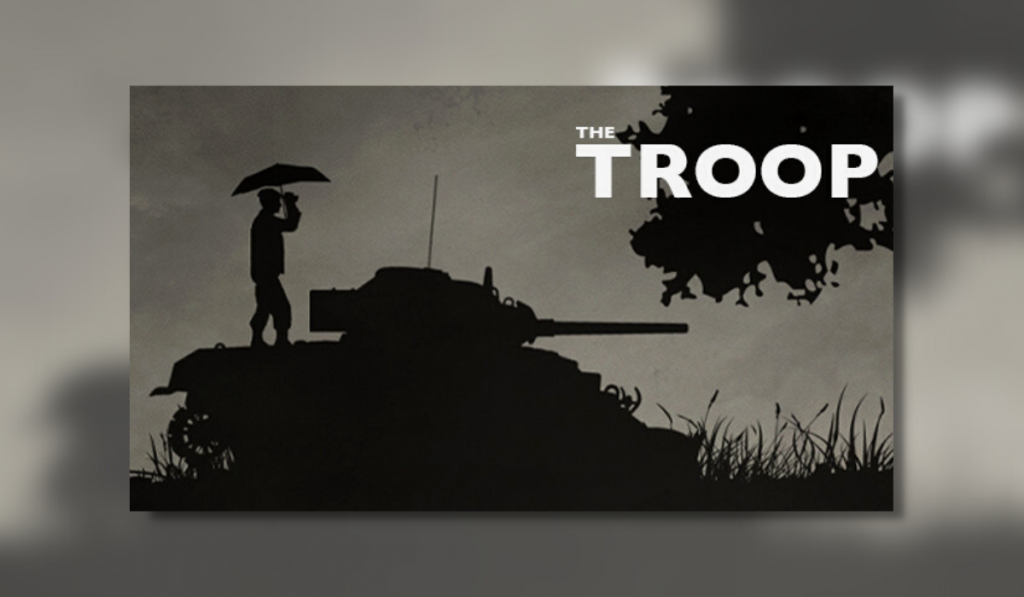 The feature image for The Troop. The Image shows a man standing on the back end of a tank holding an umbrella. The background is a dark olive green .