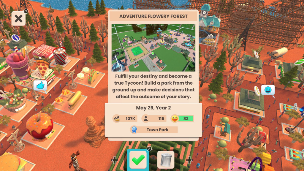 screenshot showing a desert style theme park with rich orange paths and land. Green trees adorn the paths while I multitude of shops and stalls occupy the spaces. In the centre is a pop up window that shows the game progress that I am loading. 
