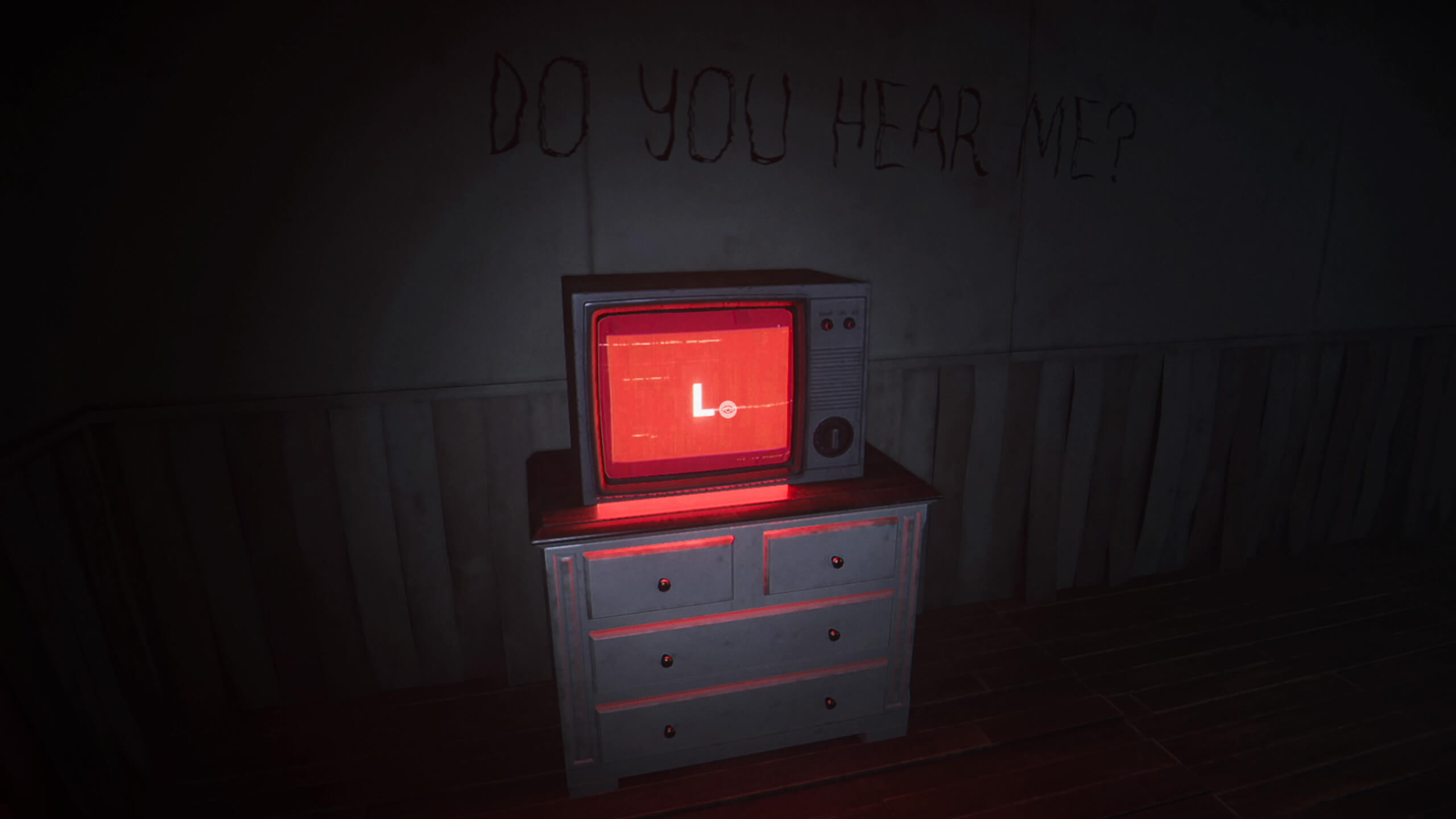 An old box television sat atop a white chest of drawers in a dark room. The TV is glowing red with the letter L on it in white. Behind the TV are the words "DO YOU HEAR ME" scrawled in black on the wall.