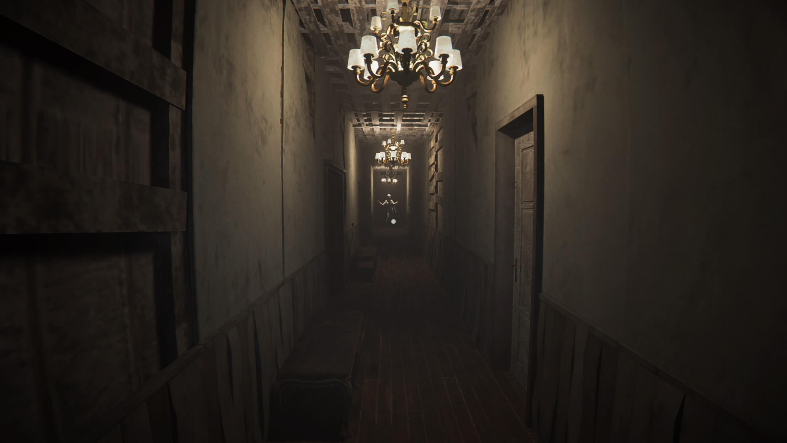 A dimly lit shabby corridor. On the ceiling are three small chandeliers spaced out from each other going vertically. At the end of the corridor is a mannequin with multiple arms. 