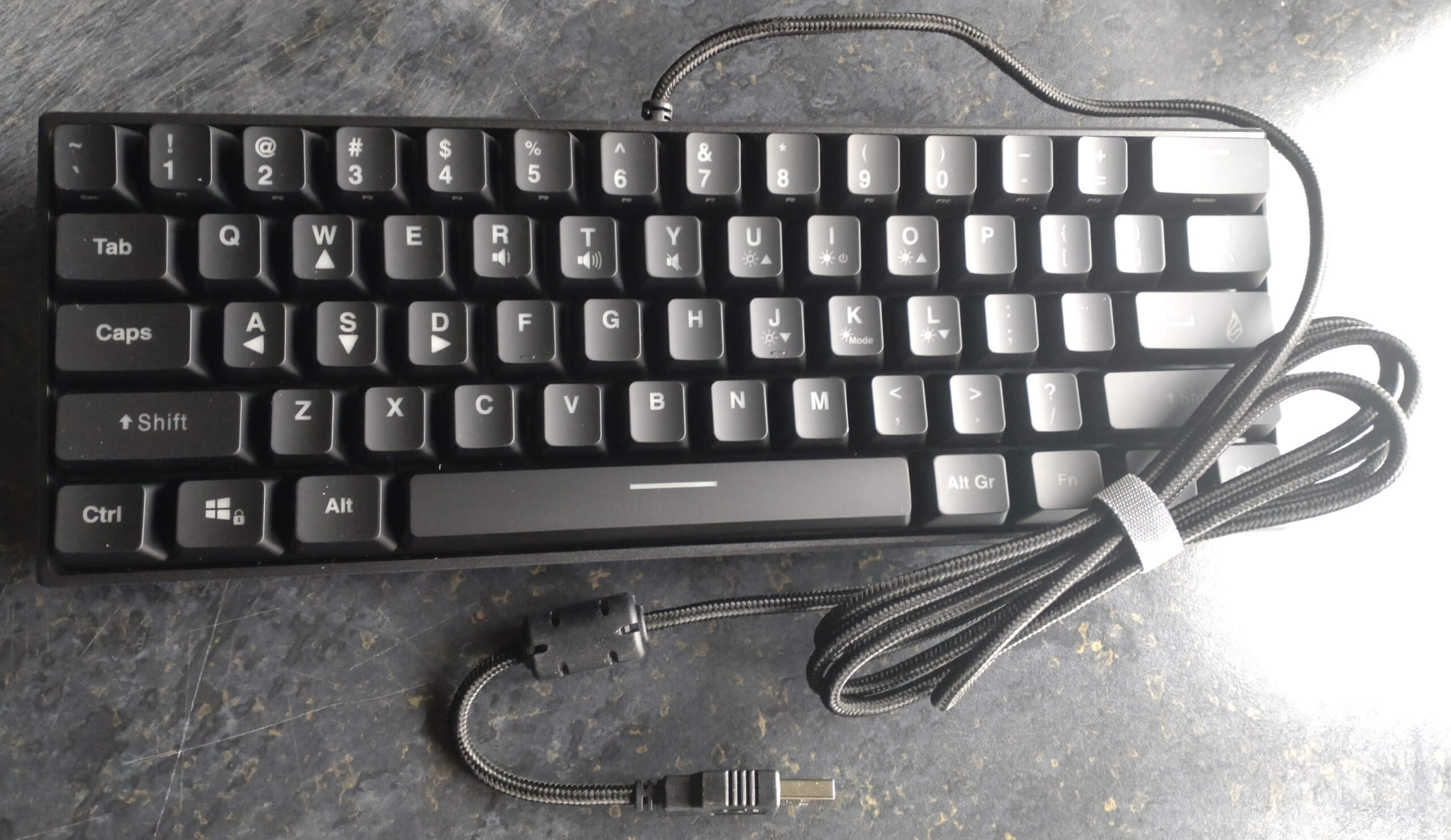 The Surefire Kingpin M1 Mechanical Keyboard with its tied USB cable beside it.