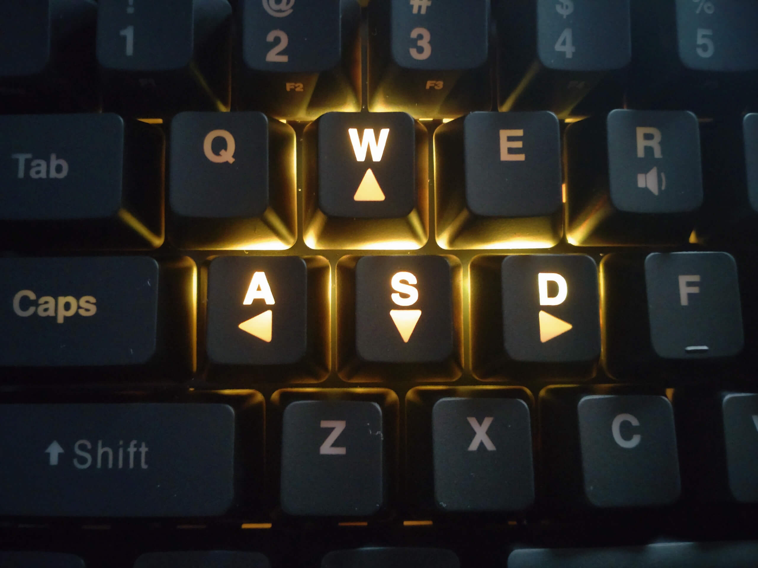 A closeup of the WASD keys on the keyboard. The rest of the key's lights are off, while the WASD keys are glowing gold.