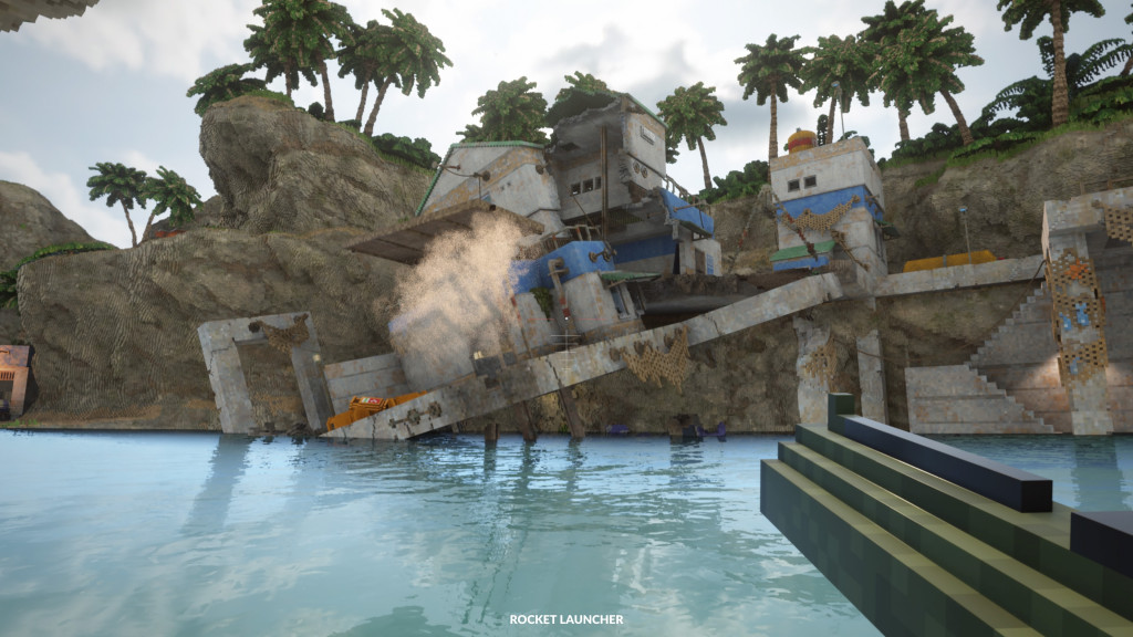 screenshot showing a grey and blue building that was on a raised platform slumped into the blue water. Smoke pours out from the cracks. A line of green palm trees are behind on a raised cliff top.