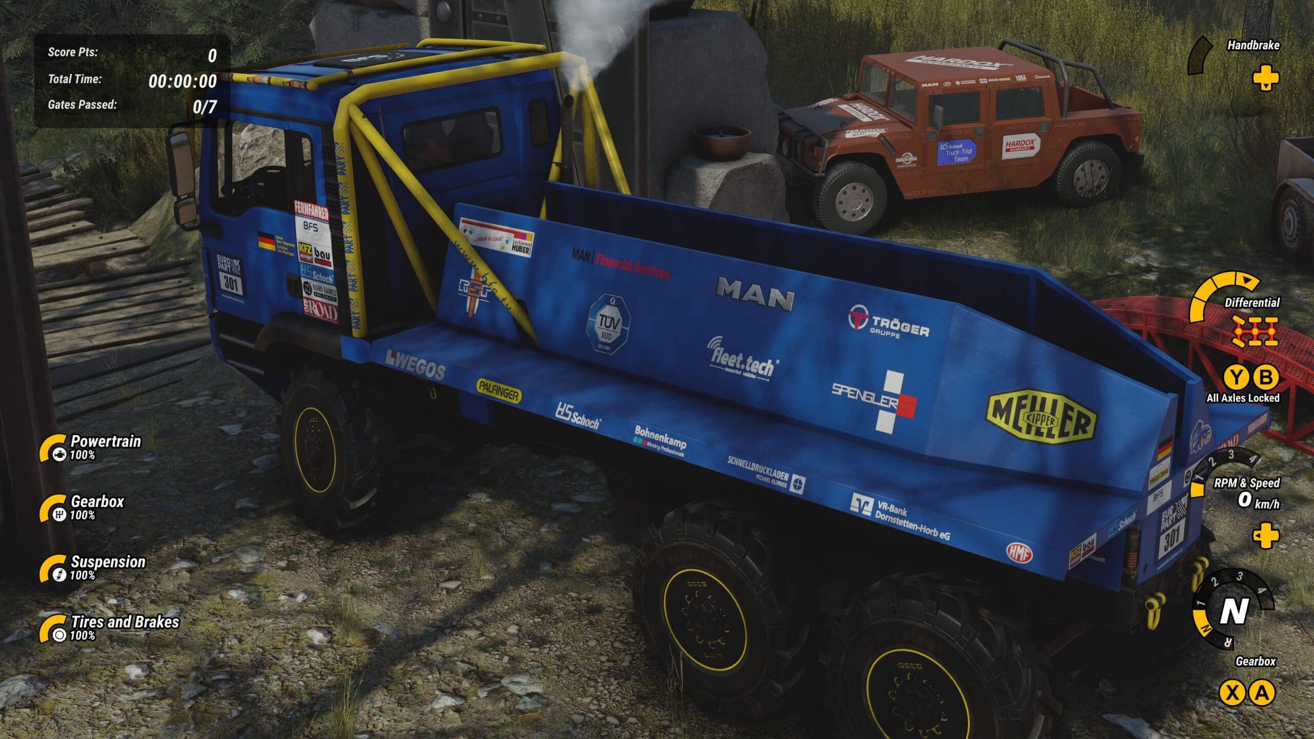 A blue heavy duty 3-axle truck is shown at the starting area of a challenge course. The area around it is rocky. Status of different truck parts are displayed down the left side of the screen while RPM/gears and axle settings are along the right.