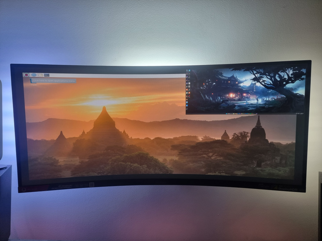 photo showing PiP on the monitor screen. There is an image of the PC desktop displayed in the top right of the screen while the remaining area is showing a sunset temple wallpaper from the Raspberry Pi.