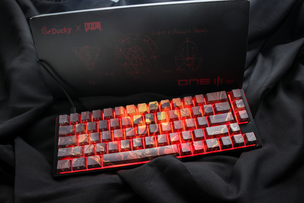 A picture of the keyboard laid in front of it's box, powered up and with it's LED lights lit up red.