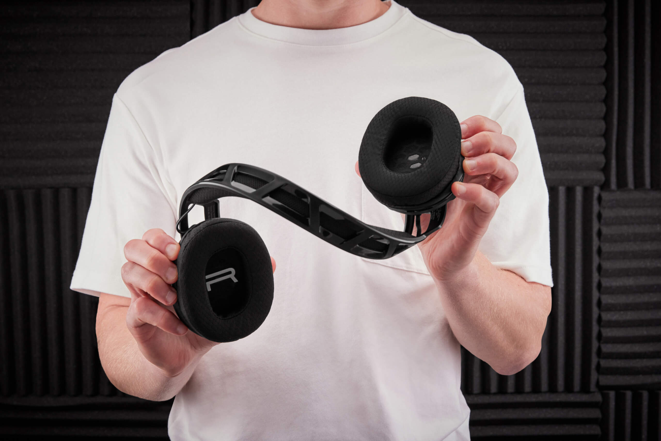 a person in white tee twisting the headset band to show how durable is it