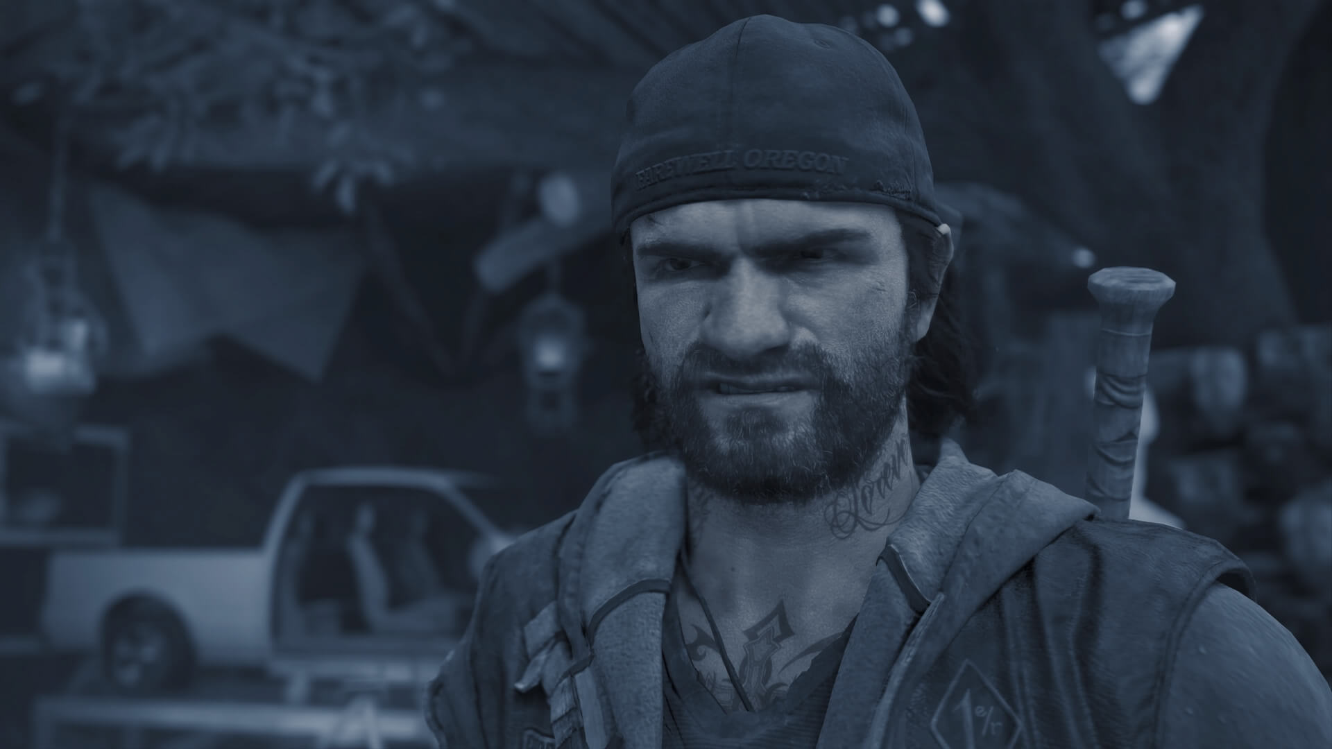 a close up of Days Gone main protagonist Decon St John. He has a growling look on his face and is carrying a baseball bat on his back