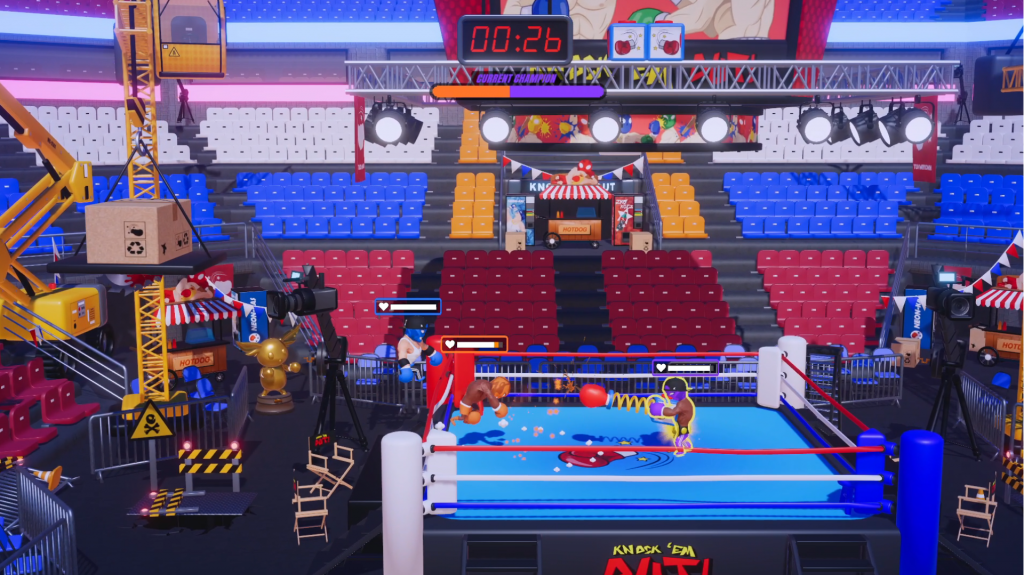 A wrestling arena with three combatants fighting centre screen. Lighting rigs, cranes and work in progress signs clutter the outside of the ring.