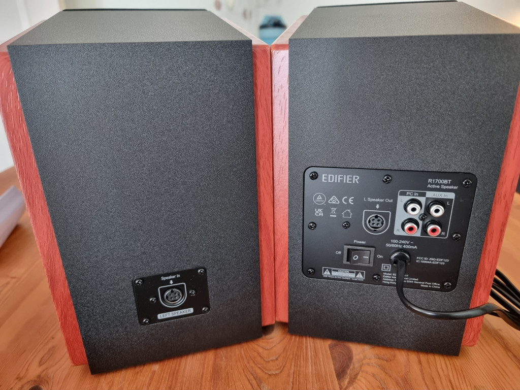photo showing the rear of the Edifier speakers. There is a main powered speaker on the right with power, 2 rca aux sets for incoming signal and a connection socket to the passive speaker.