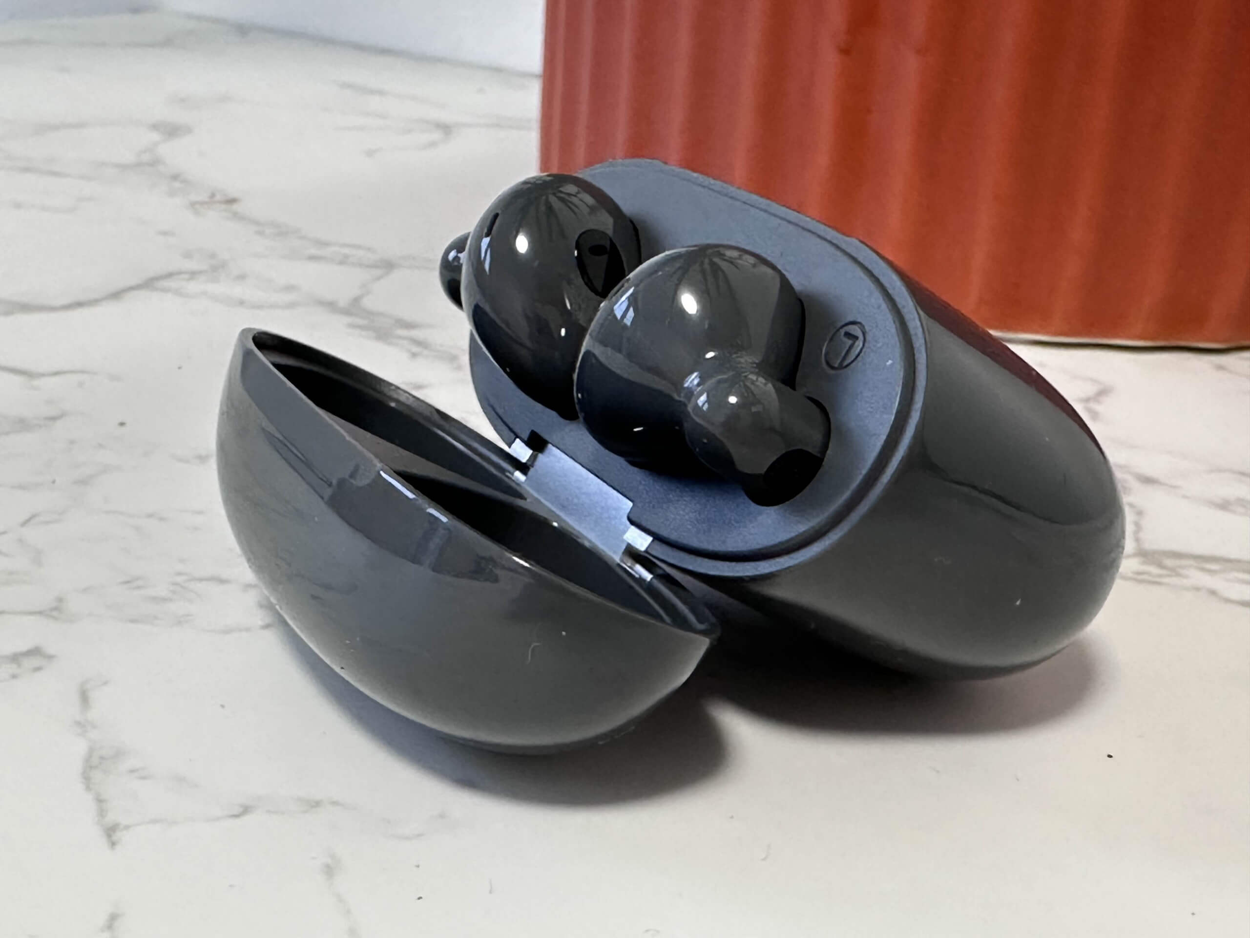 Edifier W320TN wireless earbuds in an open charging case on a marble surface.
