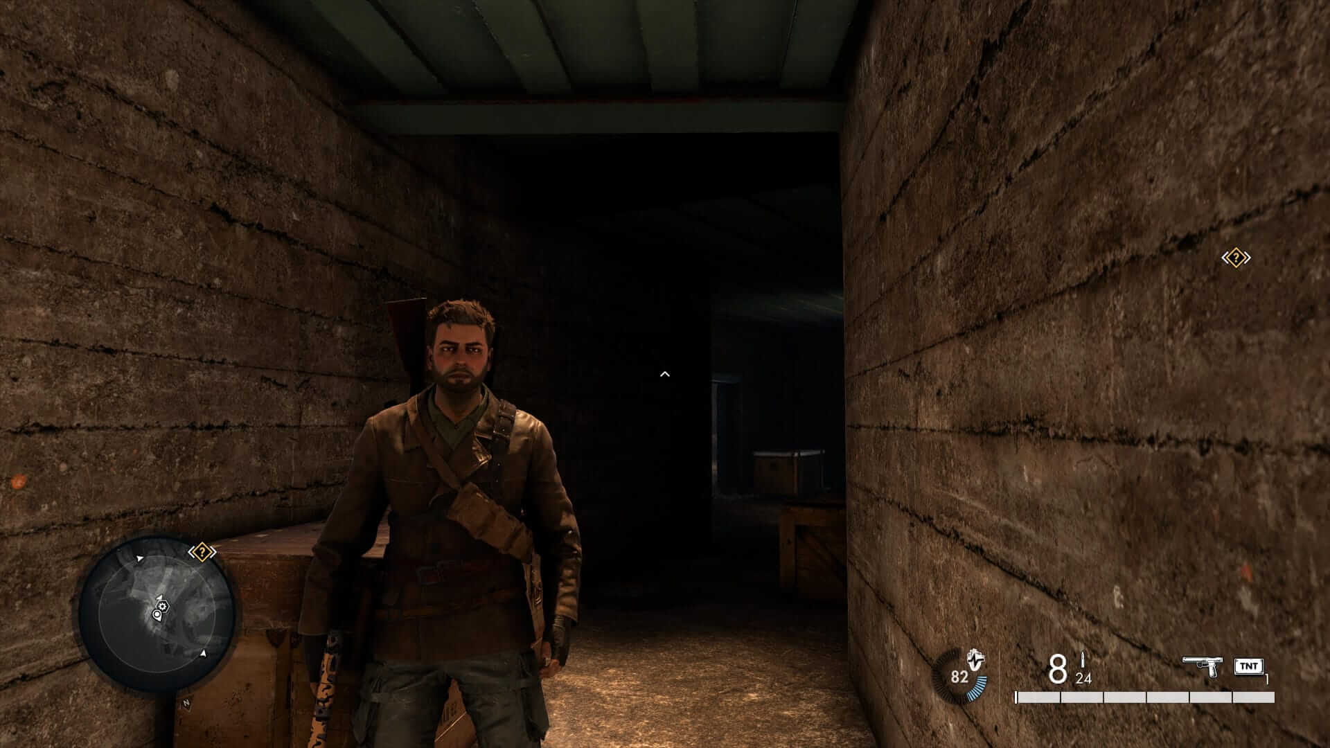 A man with brown hair and beard is standing in a bunker corridor looking at the camera