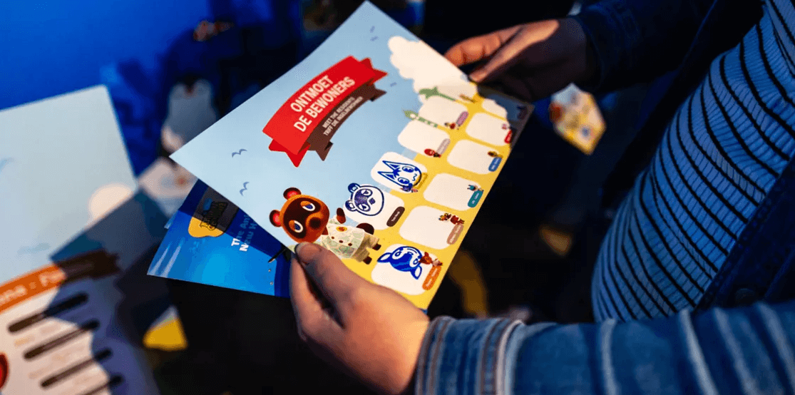 Photo of a child's hand holding a Sea Life Animal Crossing: New Horizons event leaflet and activity book.