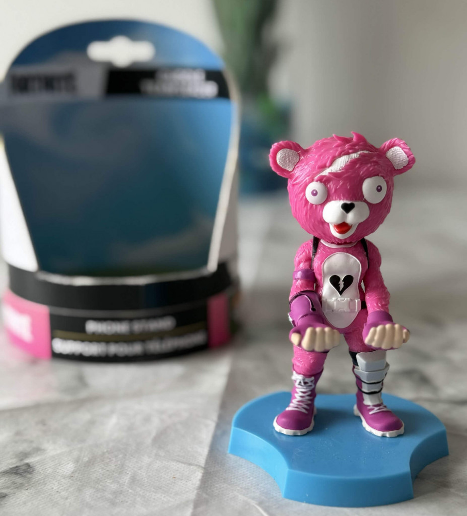 Picture of cable guys holdem cuddle team leader. A pink bear figurine with big eyes and a heart symbol on its chest stands on a blue base, with its packaging partially visible in the background.
