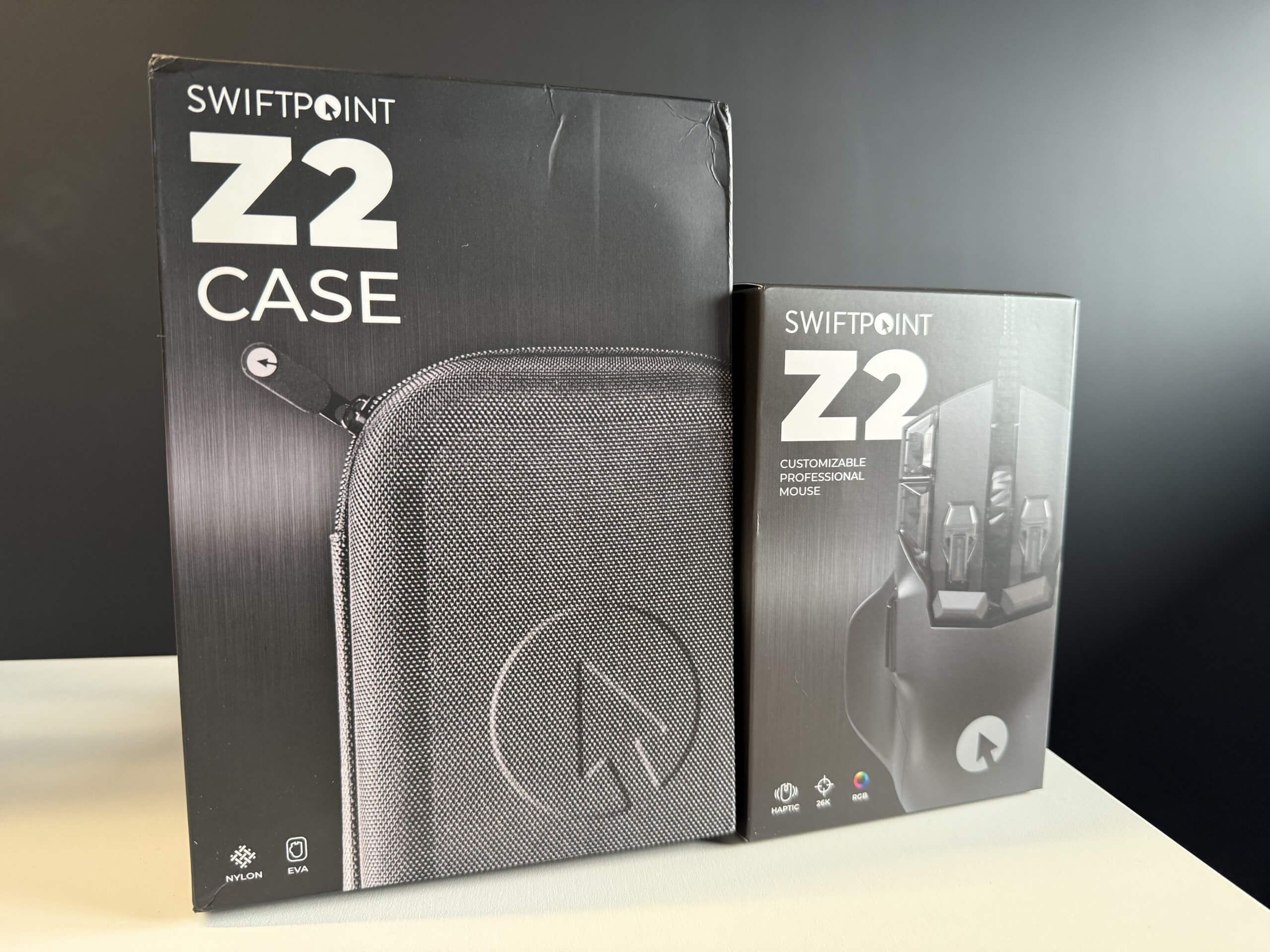 Two Swiftpoint Z2 product boxes: a case on the left and a customizable mouse on the right, both featuring sleek black designs.