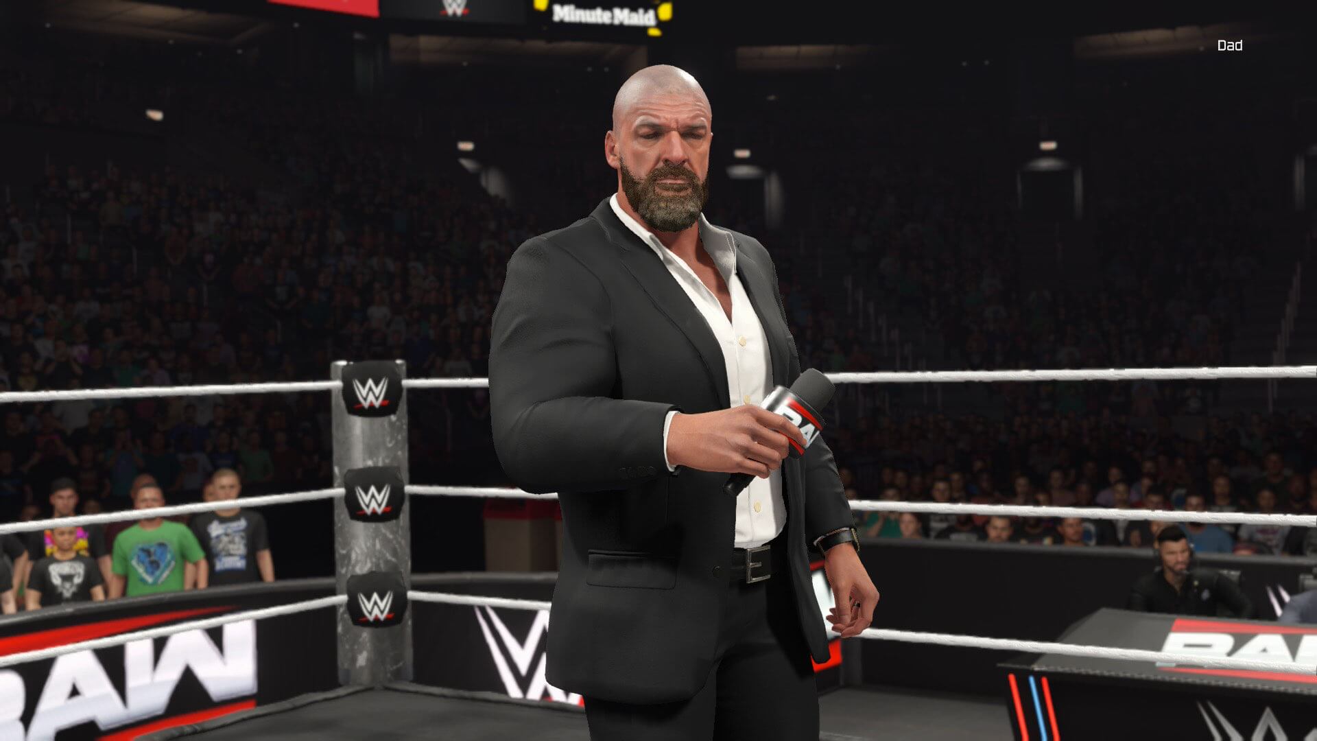 Screenshot of WWE 2k25 switch 2 edition. WWE Chief Content Officer Triple H stood in a wrestling ring holding a microphone, surrounded by a crowd of people in an arena.