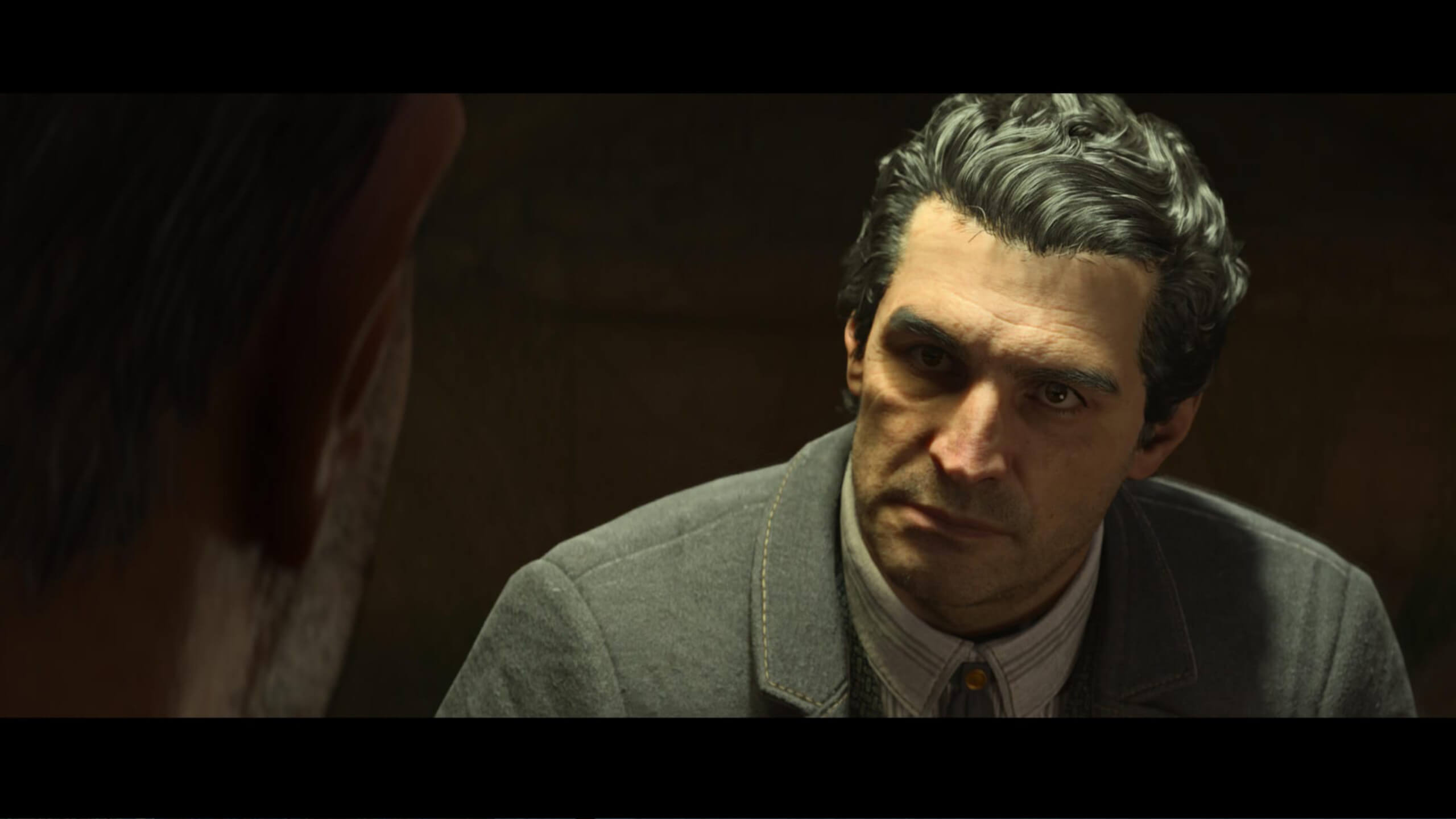Screenshot from Mafia: The Old Country. Animated scene depicting a serious-looking man with slicked-back hair, wearing a suit. He faces another person, creating a tense, contemplative atmosphere.
