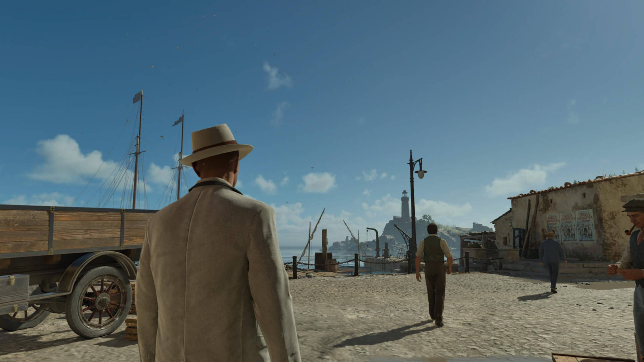 Screenshot from Mafia: The Old Country. A man in a suit and hat stands at a sunlit harbour, looking at the sea under a clear sky. Three other men walk nearby, adding a vintage feel.