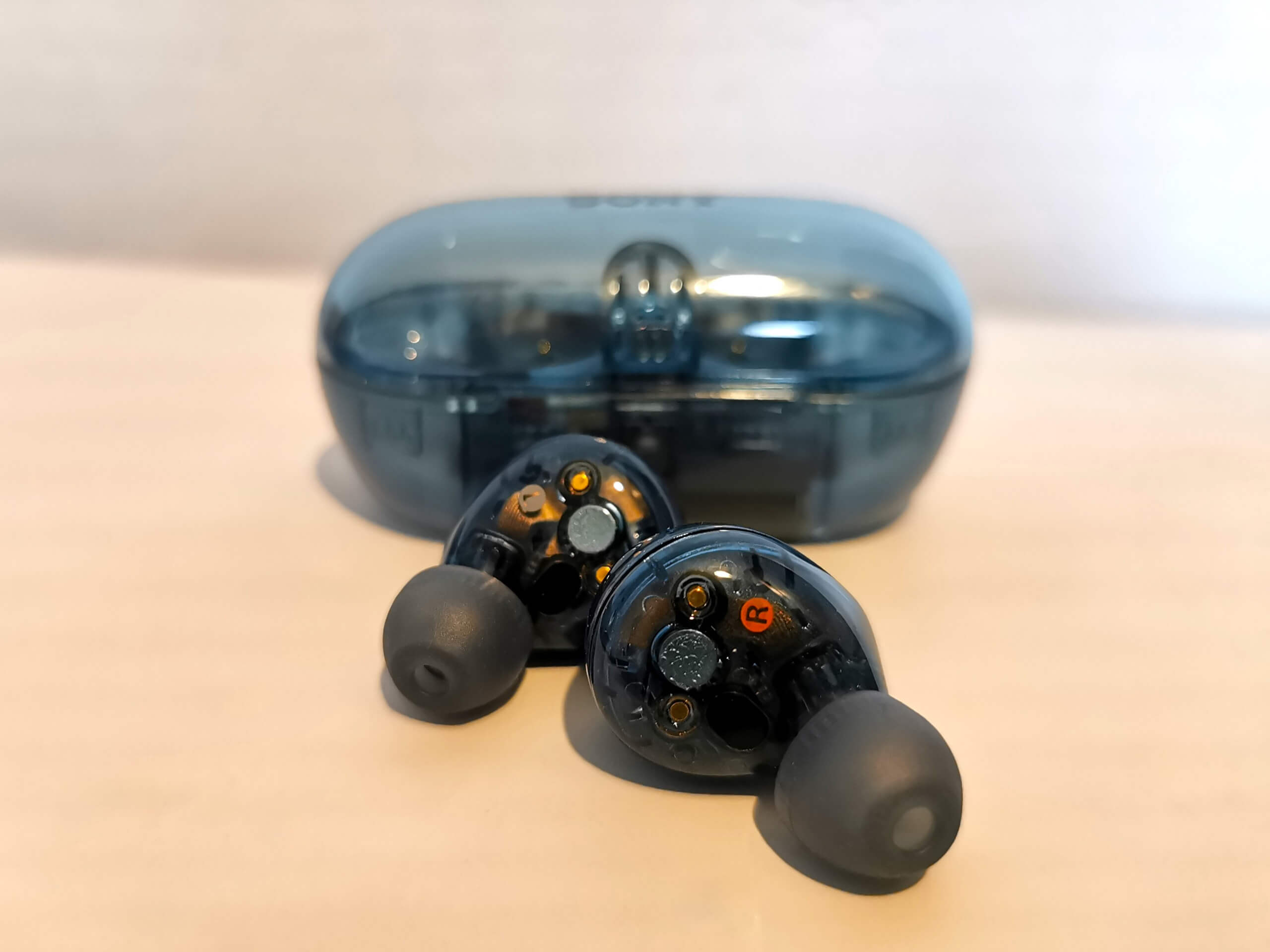 The Sony WF-C710N earbuds in transparent blue pictured in front of their closed case, showing the Left and Right lettering on each earbud over a white background