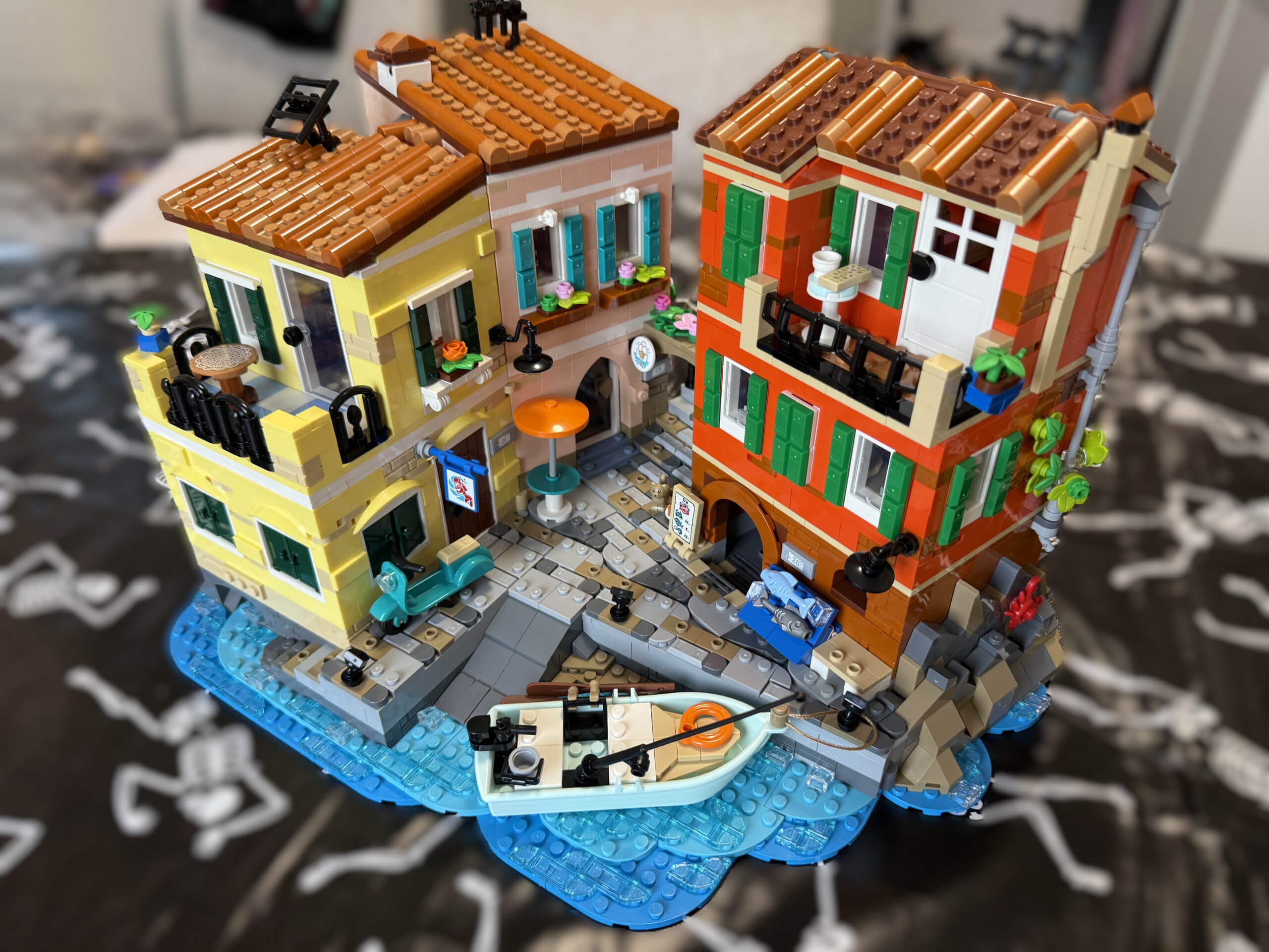 A front on view of fully built LEGO Italian Riviera featuring a boat on brick built lake and bright brick built buildings