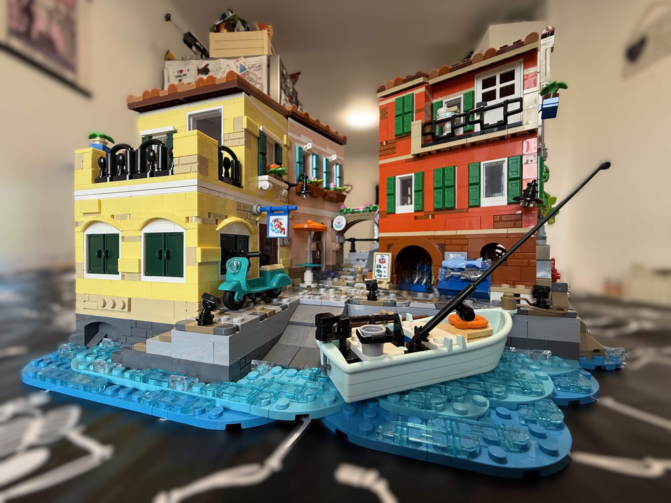 A front on view of fully built LEGO Italian Riviera featuring a boat on brick built lake and bright brick built buildings