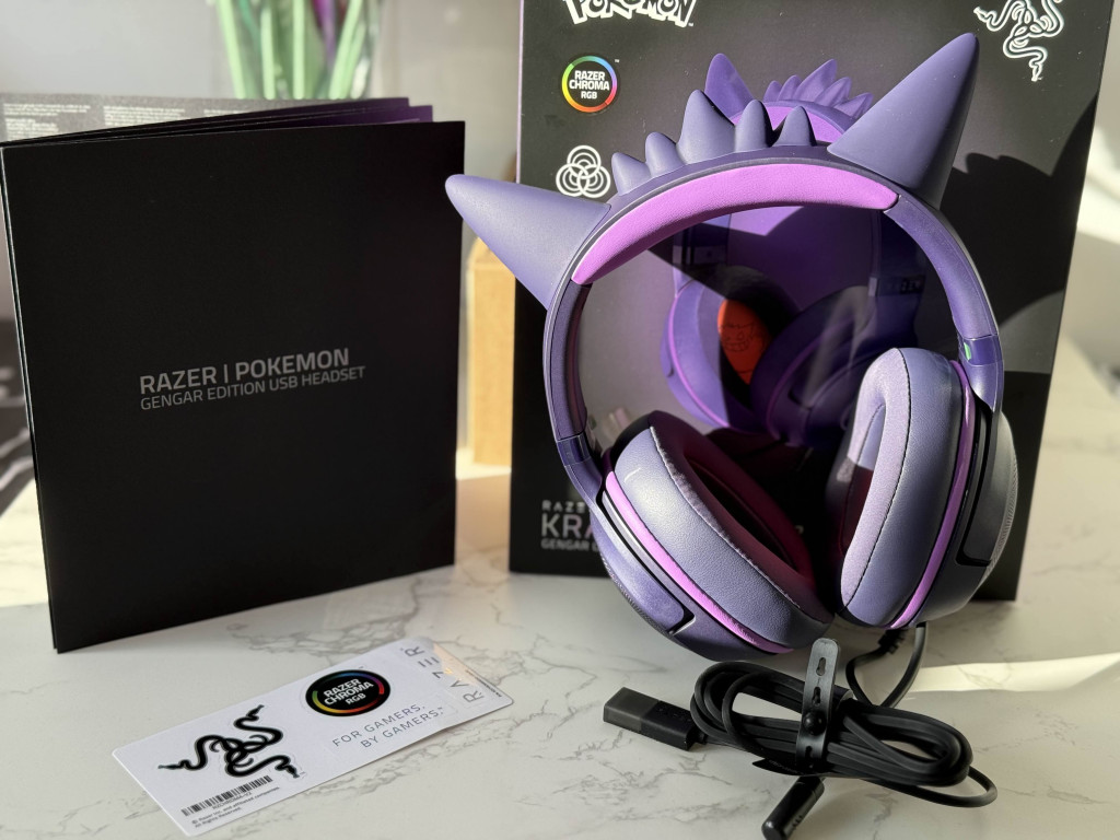 A Gengar Edition USB headset by Razer, featuring purple accents and playful spikes, displayed alongside its packaging and accessories.