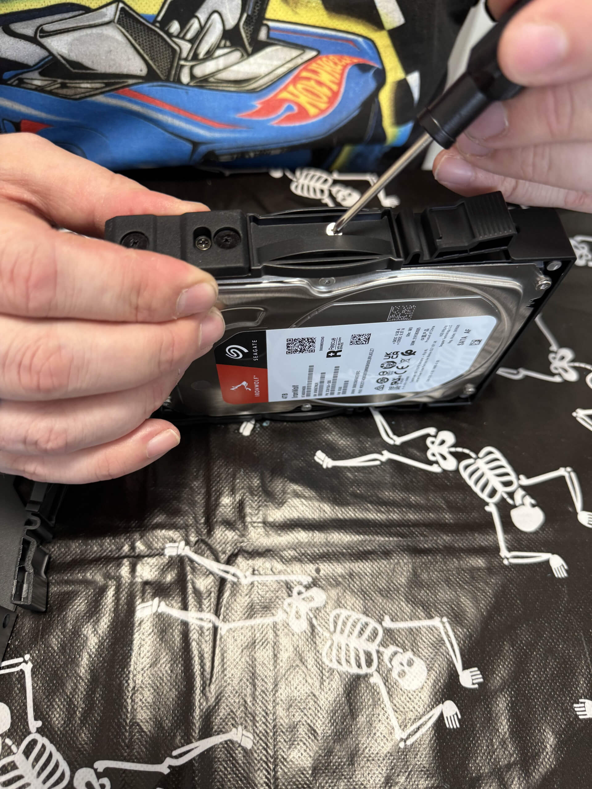 image showing one of the hard drive brackets being attached by screw to a 3.5 inch HDD