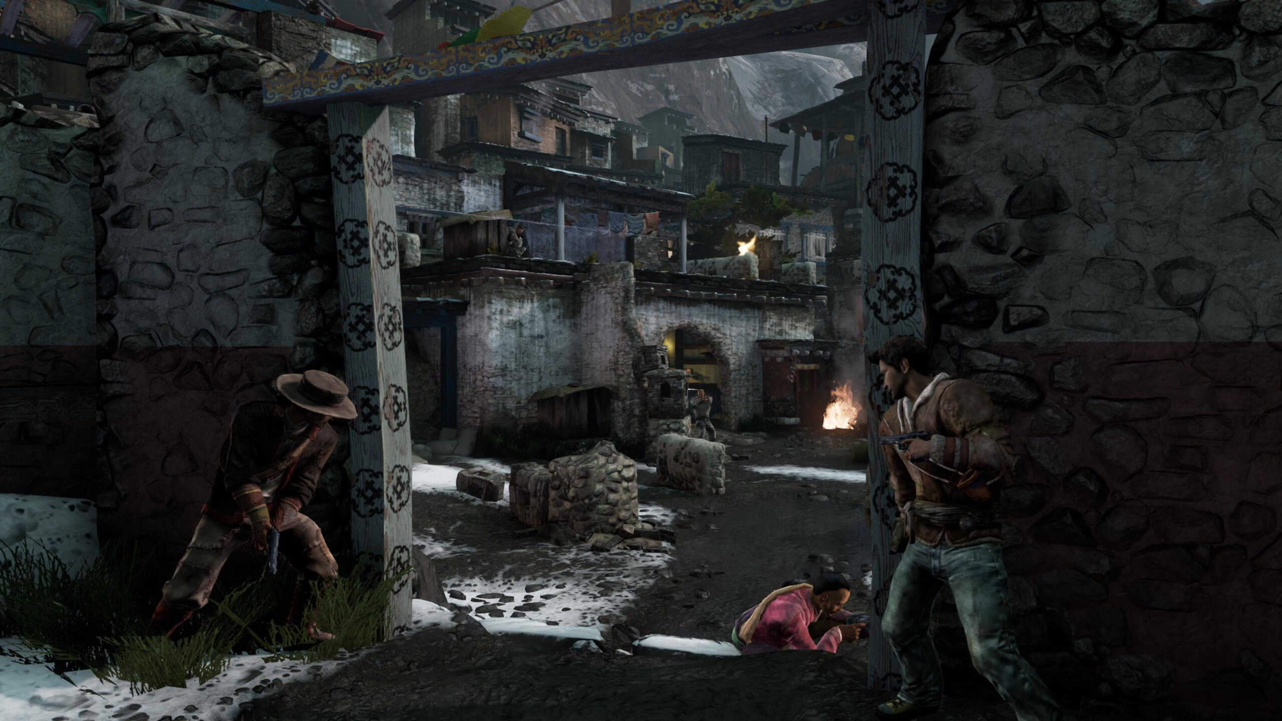 Screenshot from Uncharted 2: Among Thieves. 2 characters take cover at either side of a large doorway, looking out into a sprawling, concrete village of small buildings.