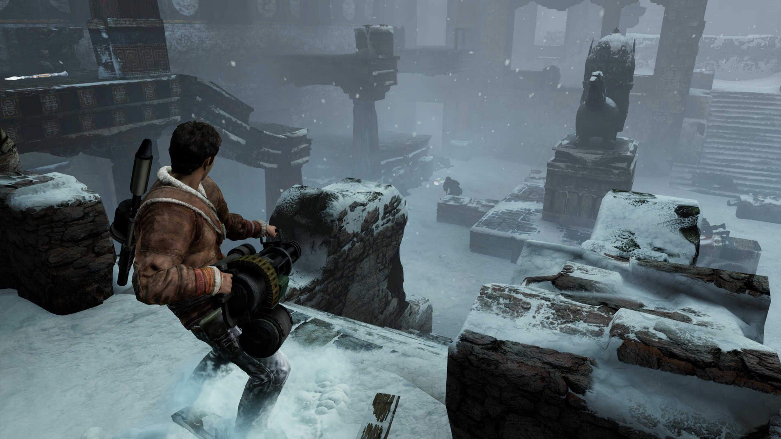 Screenshot from Uncharted 2: Among Thieves. Nathan Drake stood in some snowy ruins holding a large Gatling gun, big enough to require two hands to support it's weight.