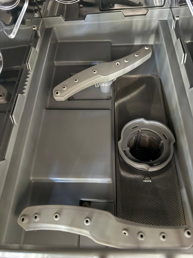 Close-up of the grey appliance interior featuring a removable filter, hoses, and a compartment for a water reservoir.