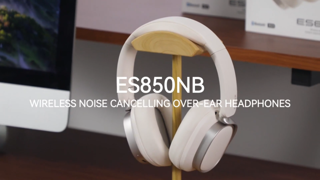 Edifier ES850NB noise cancelling over-ear headphones written in white text in front of the Edifier ES850NB headphones themselves also in white, sat wooden headphone stand. Sat on a PC desk