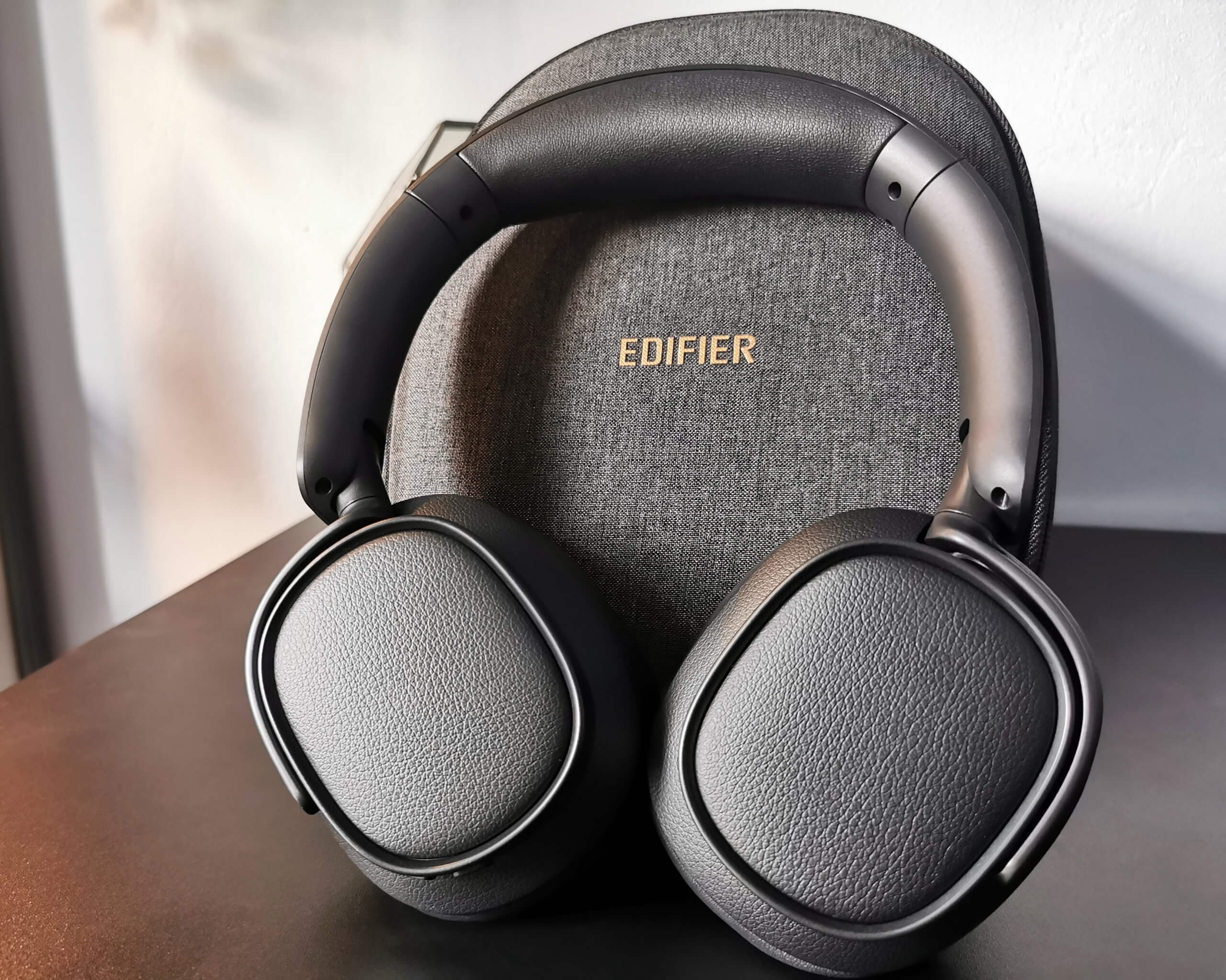 Edifier ES850NB pictured in black lent up against their grey soft case on a black desk