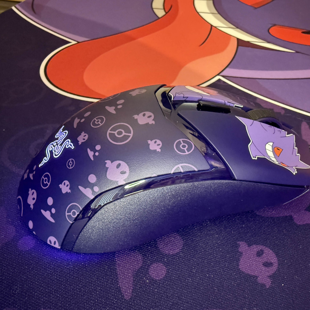 A purple razer cobra gaming mouse with Gengar graphics and playful designs rests on a matching mouse pad featuring a spooky aesthetic.