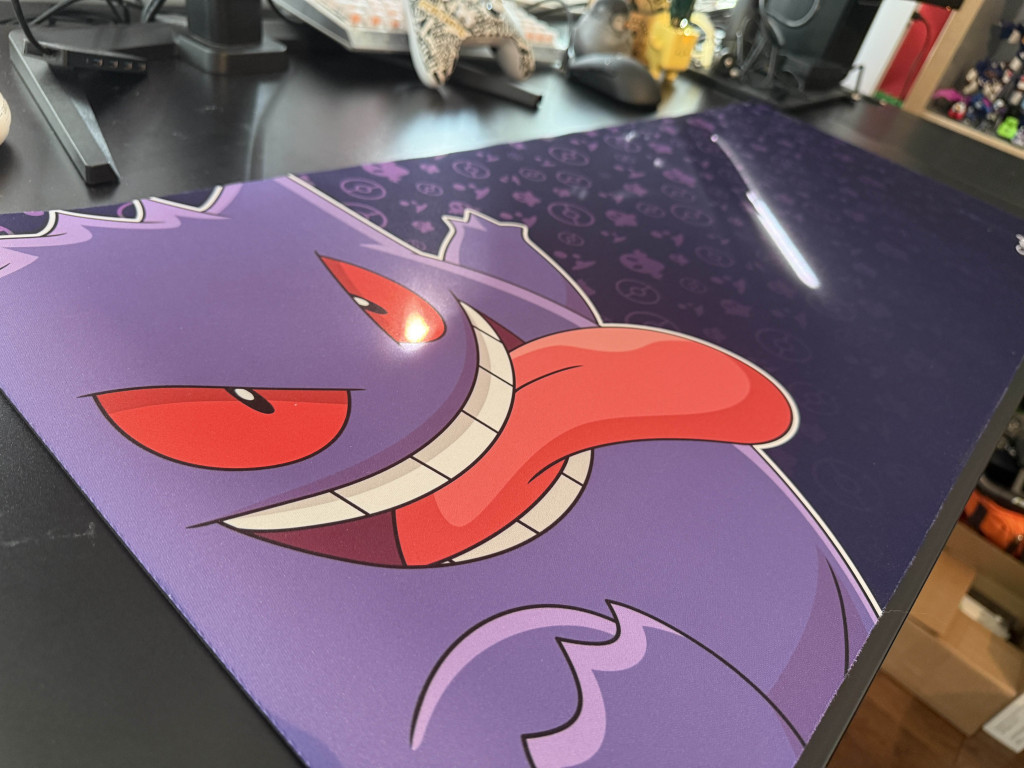 Close-up of a colourful Razer Gigantus V2 Gengar Edition mousemat featuring the Pokémon's mischievous face, set on a dark, playful background.