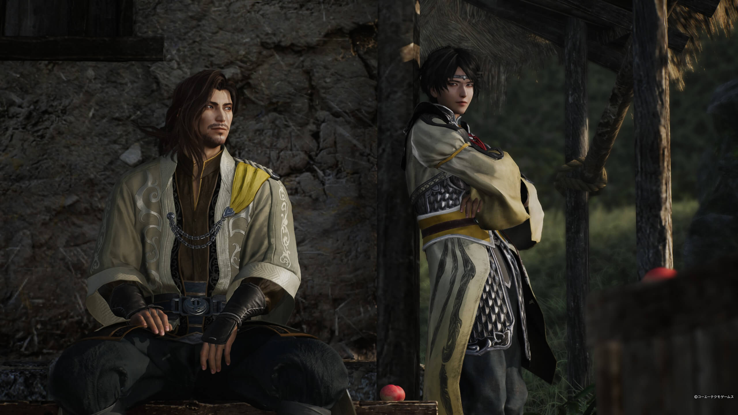 Two men looking at each other outside a hut. Both are wearing lightly yellowish robes with the man on the right wearing chain mail.