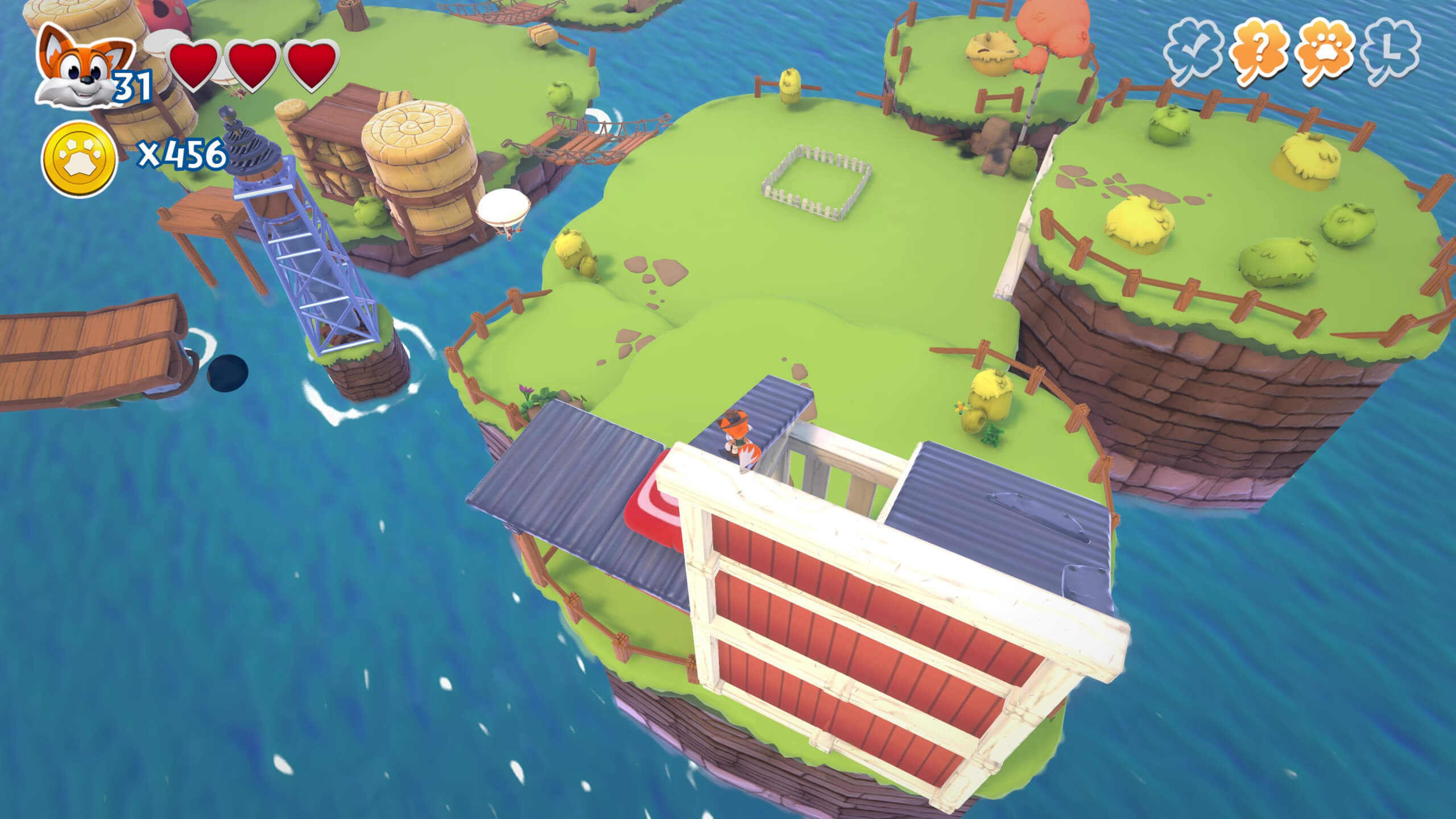 A birds eye view of a farmyard island with green grass, yellow chickens, a red wooden barn and blue water.