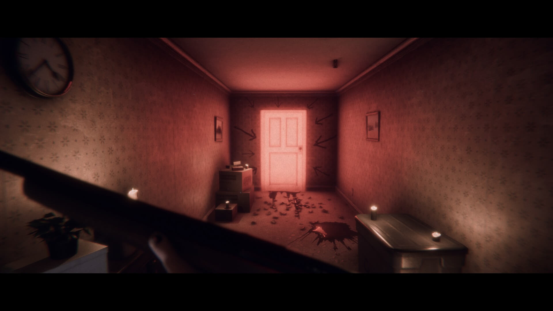 A long hallway with a glowing red door at the end. Around the door are arrows pointing towards it. Blood is seen on the floor, nearby some boxes. The player is holding a rifle in their hands.