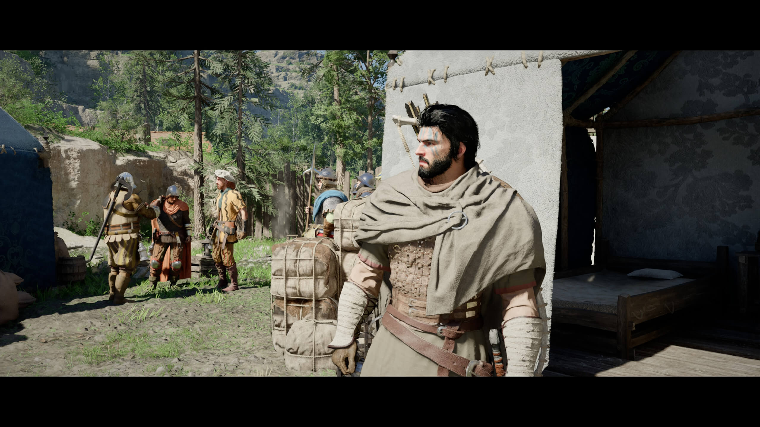 Kliff is looking to the left somewhere. In the back are five men in armour, three are talking while two are standing guard. A forest is seen further in background.