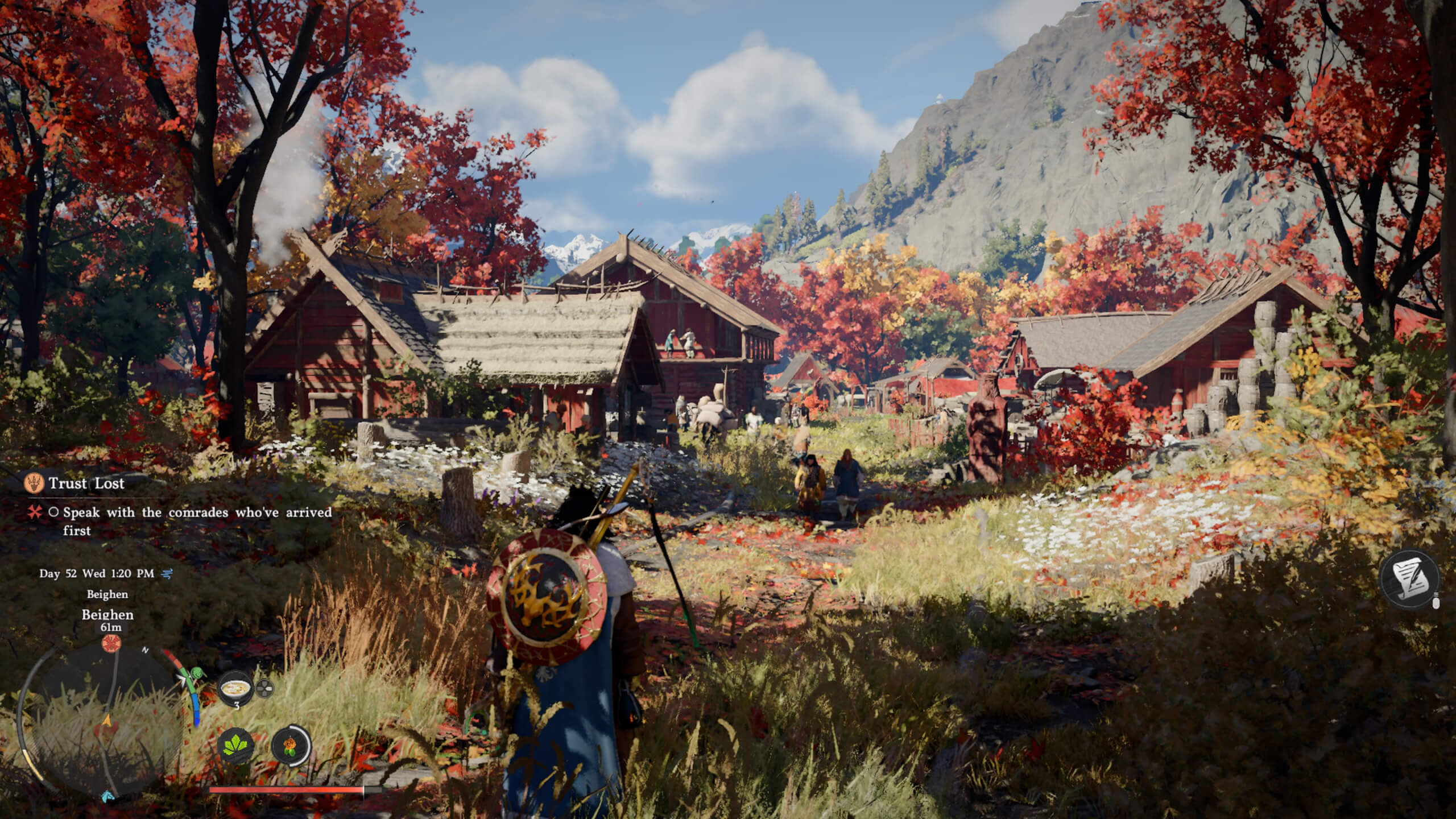 Kliff, wearing a light blue cape and a black and gold shield on his back, stands in long grass with a small village ahead. The entire area is autumnal, with red and orange leafed trees scattered about. In the background is a mountain on the left, and a bright blue sky with clouds on the left. The villages' houses are red and barn-like aesthetically with white trims, and thatch roofs. There's also a lot of white flowers growing amongst much of the grass.