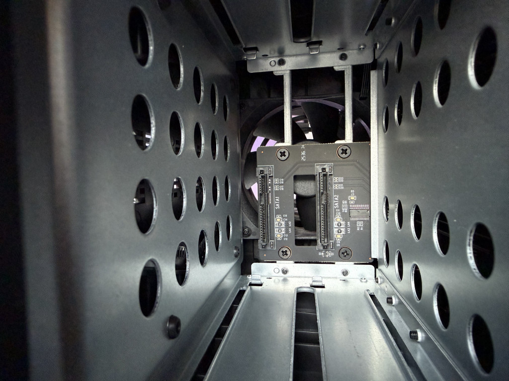 Close-up of the inside of a computer case, showing metal mounting brackets with circular holes and an electronic component with connectors.