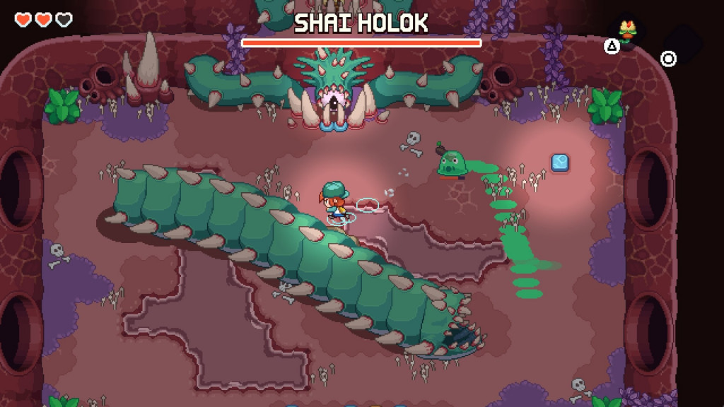 Nia fighs a large, spiked worm-shaped boss named Shai Holok. A smaller, gelatinous enemy is following her, whilst a one-eyed monster stares at her, attached to the wall.